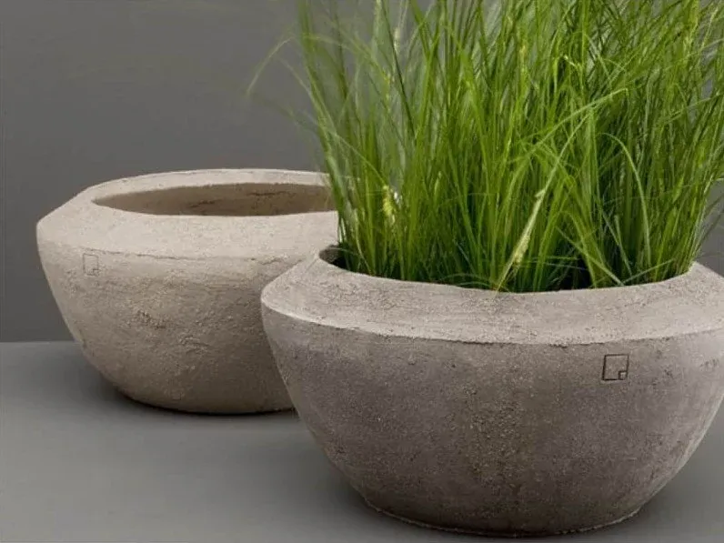 Twee grijze betonnen schalen, één beplant met siergras