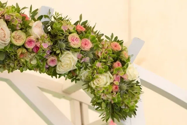 Slinger van roze en witte rozen op een witte stoel