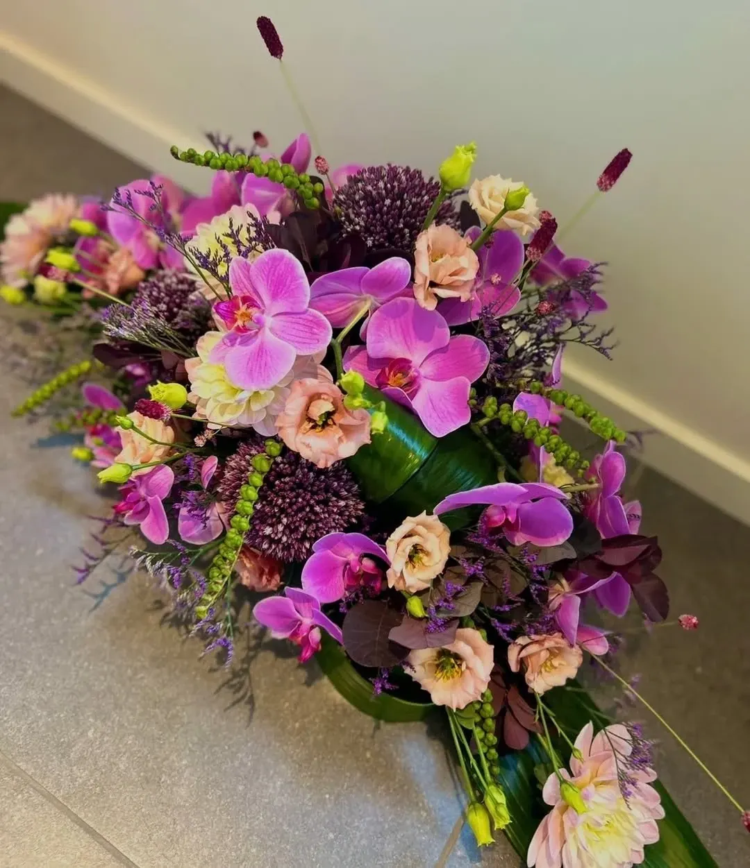Bloemstuk met roze orchideeën, lisianthus en paarse allium