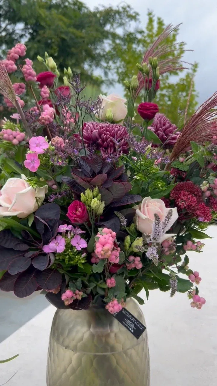 Boeket in roze en dieppaars met rozen en anjers in een glazen vaas