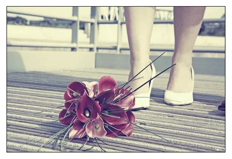 Bruidsboeket van bordeauxrode calla’s naast witte schoenen
