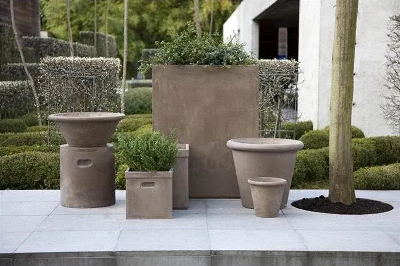 Taupe buitenpotten in verschillende vormen op een terras