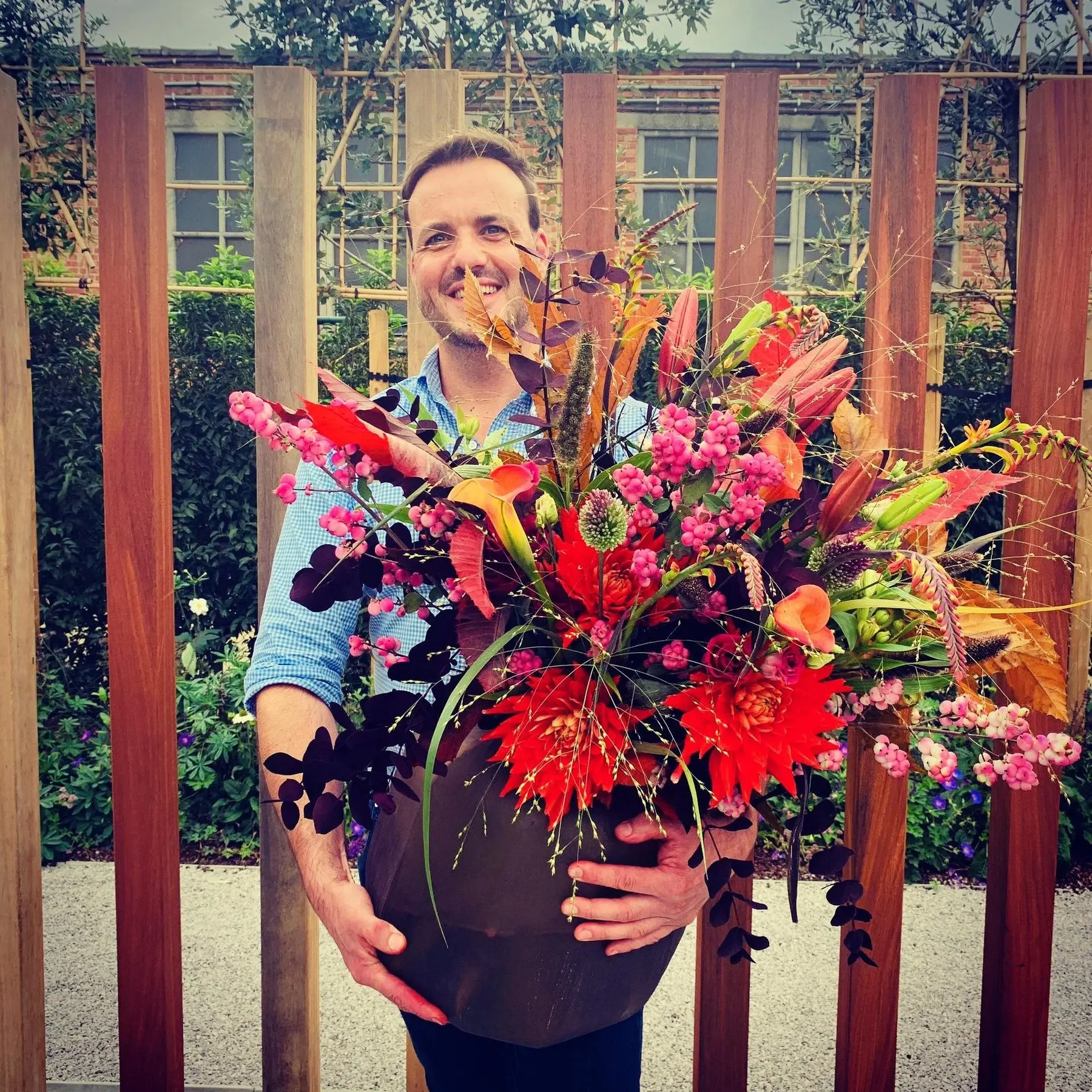 Groot herfstboeket met dahlia’s, lelies en pluimgrassen in een donkere vaas