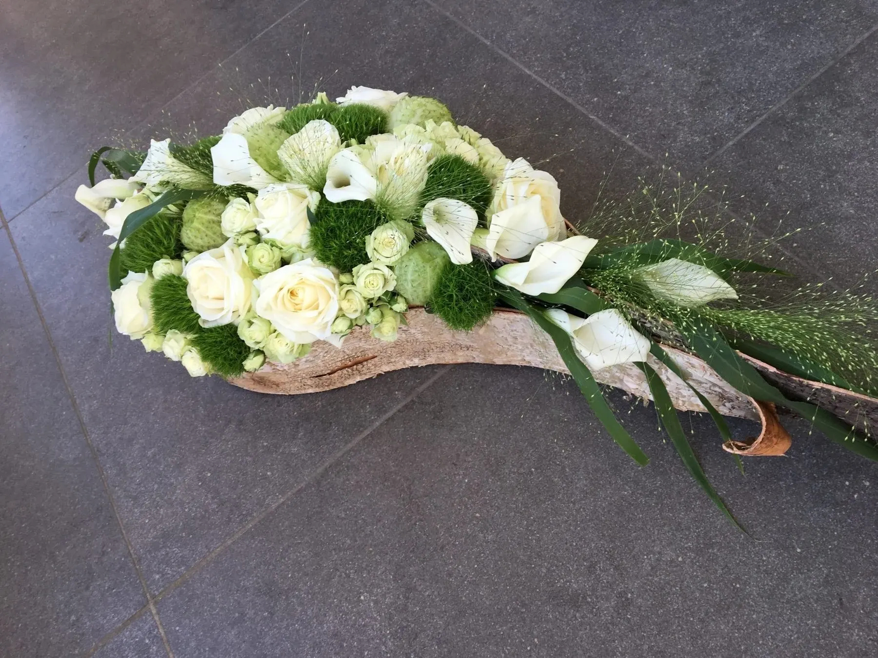 Rouwstuk van witte calla’s en rozen in een gebogen vorm