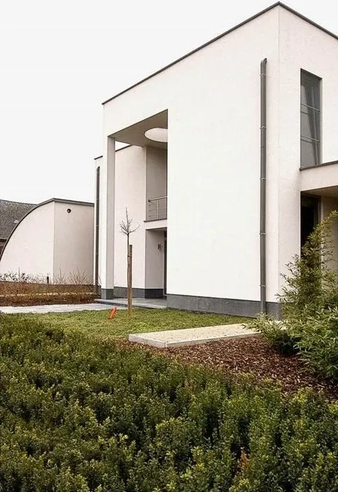 Moderne witte villa met lage hagen en een jonge boom