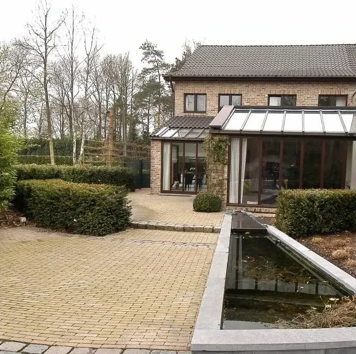 Vijver met hardstenen rand naast een terras en een veranda
