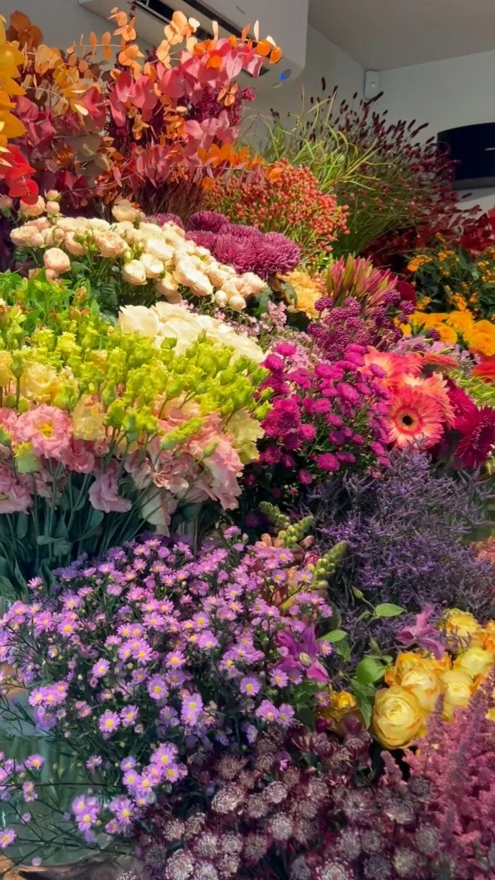 Emmers vol verse snijbloemen in de winkel: rozen, chrysanten, gerbera’s en asters in warme kleuren